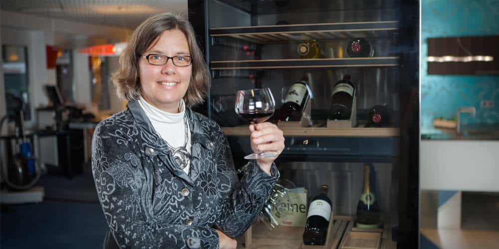 Christiane Richter mit Glas Rotwein vor Ausstellungsküche